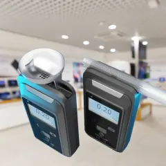 Dwa alkomaty z wyświetlaczem pokazującym 0.20, jeden z ustnikiem, na tle sklepu.